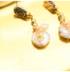 Macro detail of baroque pearl earrings with 18k gold plating and crystal bead strings