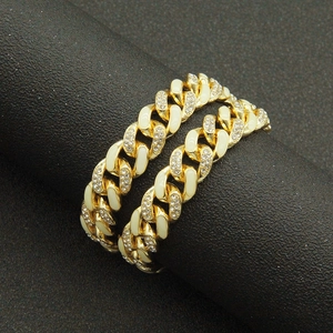 Close-up of gold Cuban chain links featuring cream enamel and sparkling rhinestones