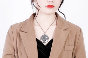Close-up of a silver hollow Tree of Life pendant necklace worn by a fashion model