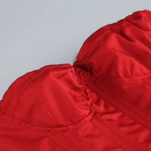 Détail rapproché des coutures et du tissu plissé rouge de ce haut bustier chic