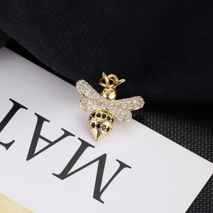 Detailed macro view of a gold bee pendant with white and black crystal rhinestones
