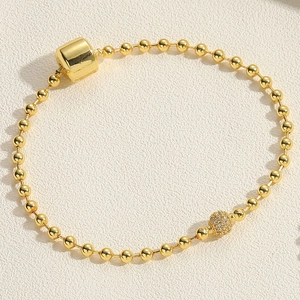 Detail of gold beaded bracelet featuring a slider clasp and a micro-pave zircon ball charm