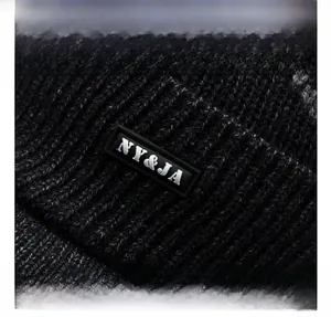 Detailed macro view of the black knit beanie fabric texture and NY&JA rubber logo patch