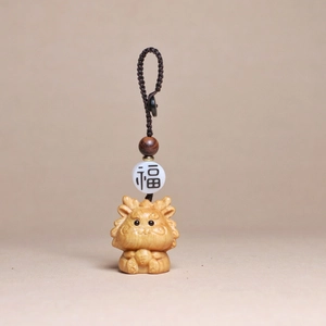Detail of hand-carved cedar wood dragon keychain with Fu character bead and braided cord