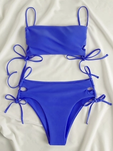 Flat lay of bright blue bikini set showing side drawstring details on a white fabric background