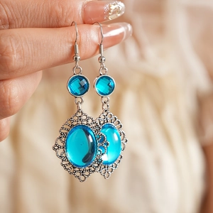 Detail of vintage bohemian silver teardrop earrings with blue resin stones held by hand