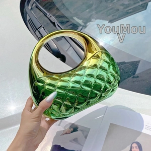 Detail of a geometric quilted gradient handbag with a round handle in green and gold