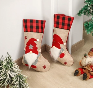 Close-up of linen and plush Christmas stockings with 3D gnome decorations hanging by a tree