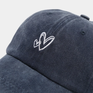 Close-up of double heart embroidery on washed navy cotton baseball cap with twill texture