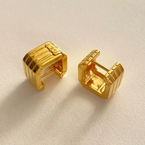 Detailed view of square gold ribbed huggie earrings with a vintage vertical grooved texture
