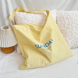 Close-up of a pale yellow canvas tote bag with blue Sunday print in a cozy home setting