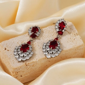 Luxurious vintage earrings with red zircon drops and silver finish on textured stone