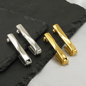 Detail of twisted bar earrings in gold and silver finish on textured dark stone