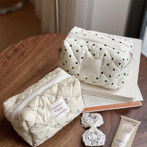 Quilted floral and heart print makeup bags in corduroy on a rustic wooden desk