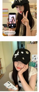 Detail of black newsboy cap featuring white ribbon bow and silver star accents