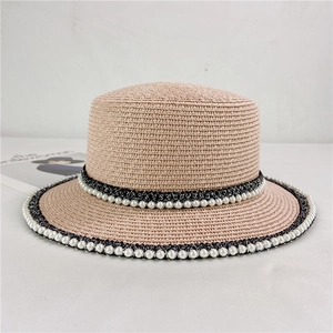 Detail of flat top straw hat with pearl lace trim and black sparkling ribbon