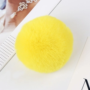 Detailed view of an 8cm bright yellow faux rabbit fur pom pom on a minimalist background