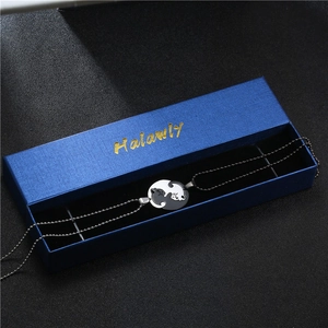 Close-up of black and white cat pendants in yin-yang design inside a blue gift box