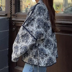 Side view of a blue and white paisley quilted jacket with V-neck tie closure
