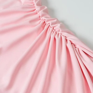 Détail de la robe en mousseline rose montrant la texture plissée fine et le tissu froncé