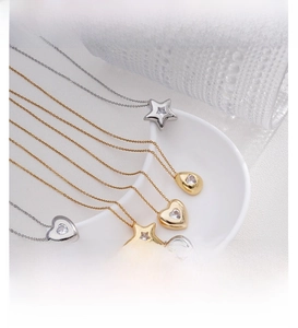 Detail of geometric star, heart and teardrop pendants with zircons on a display plate