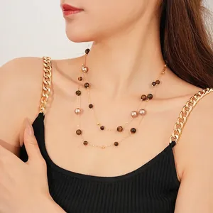 Tiger eye and pearl double layer gold chain necklace worn by a model on white background