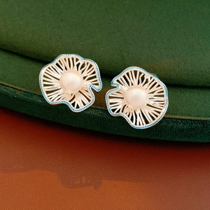 Detailed close-up of openwork flower pearl earrings with blue enamel petals and silver base