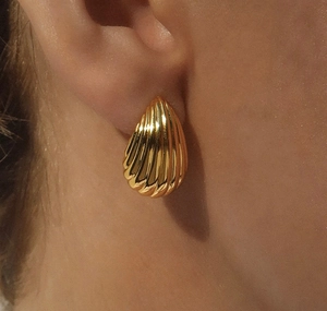 Macro detail of gold-plated ribbed teardrop earring worn by a model for trendy look