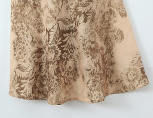 Macro shot of elegant champagne floral jacquard fabric and hem detail on satin dress