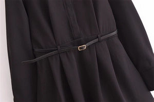 Detail shot of black long-sleeve dress featuring a matching belt with gold buckle accent