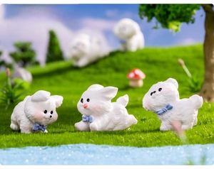 Three miniature resin puppies with blue bows on a green lawn for moss micro landscapes