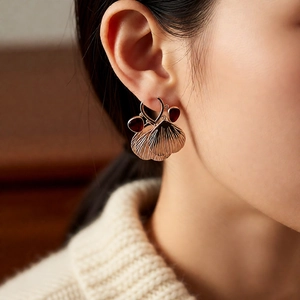Detail view of vintage gold leaf earrings with red teardrop stones on a female model
