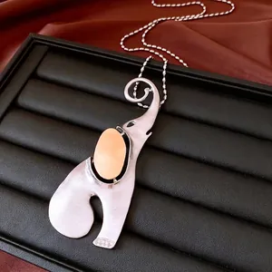 Abstract silver elephant pendant necklace with orange bead on a black leather tray