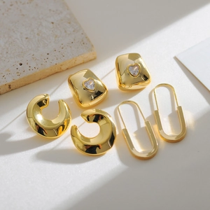 Three pairs of 18K gold plated safety pin and heart stud earrings set on textured stone