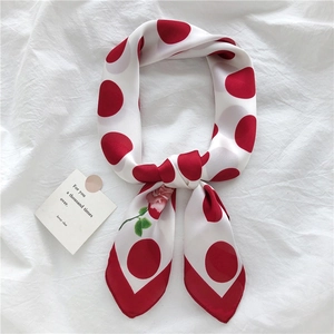 Close-up of elegant white satin scarf with large red polka dots and pink rose floral print