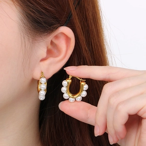 Close-up of 18k gold-plated C-shaped stainless steel earrings with white pearl inlay