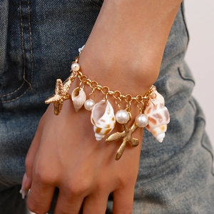 Detail of gold starfish and pearl charms on a double-layer bracelet with beach vibes