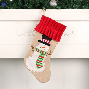 Rustic burlap Christmas stocking with snowman design hanging on a white fireplace