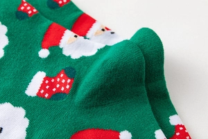 Nahaufnahme grüner Weihnachtssocken mit gestricktem Weihnachtsmann und Mustern