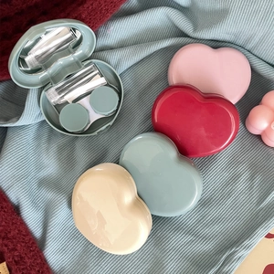 Detailed top view of heart-shaped contact lens cases with mirror and care tools