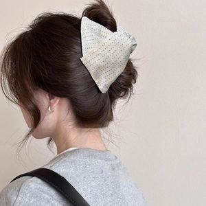Detailed back view of a polka dot bow shark hair claw clip styled on a low bun