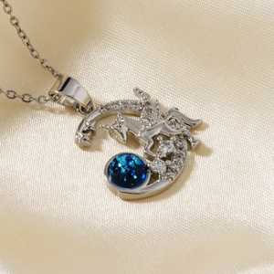 Macro detail of silver unicorn pendant with blue gemstone and diamonds on silk background