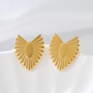 Elegant gold heart earrings with radiant sunburst design on minimalist white stand