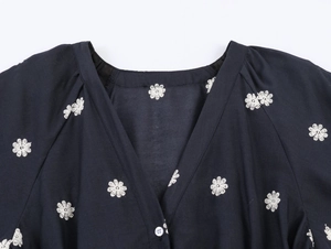 Close-up of elegant V-neckline with white floral embroidery on navy blue puff sleeve dress