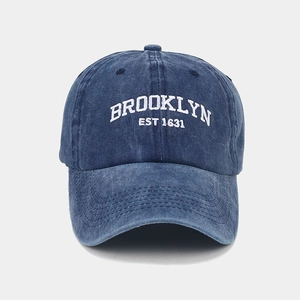 Close-up of white Brooklyn embroidery on washed navy blue cotton baseball cap