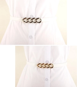 Detail of white leather belt featuring a chic gold chain buckle worn over a dress