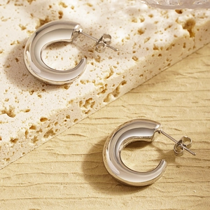 Detailed view of chunky silver C-shape earrings with a polished mirror finish on stone