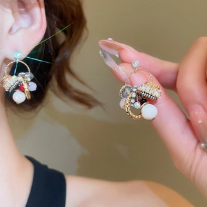 Close-up of gold hoop earrings with white pearls and sparkling multifaceted crystals
