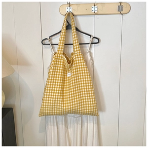 Detailed view of yellow and white checkered canvas tote bag hanging on wooden hook