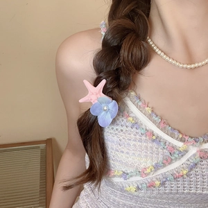 Detail of pink starfish and purple flower hair clips with pearls on a side braid